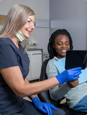 about-image-2 Dentist and patient smiling while reviewing dental results in mirror after treatment.