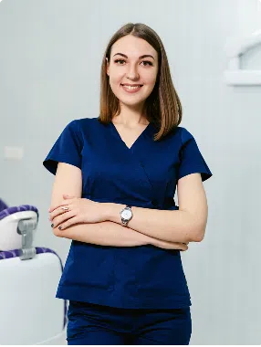 about-image-4 Confident dental professional in scrubs standing in clinic, ready to assist patients.