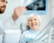 Dentist showing a dental X-ray to an older woman patient during her appointment.