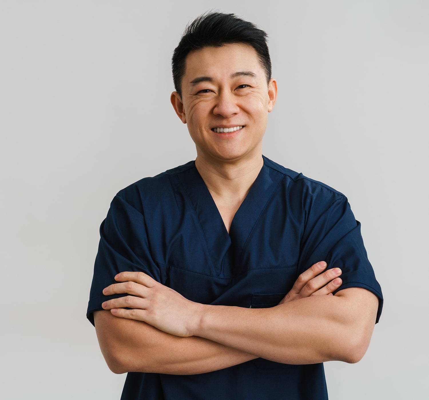 FSC-generaluse-image1-min Smiling healthcare professional in navy scrubs standing with arms crossed against a plain background.