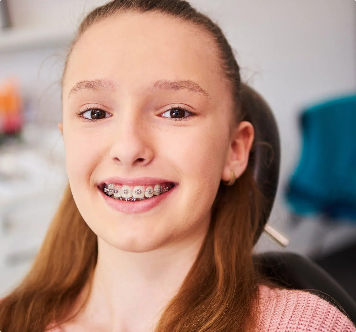 fsc-general-image (10)-min Smiling girl with braces sits in a dental chair, possibly after an orthodontic adjustment.