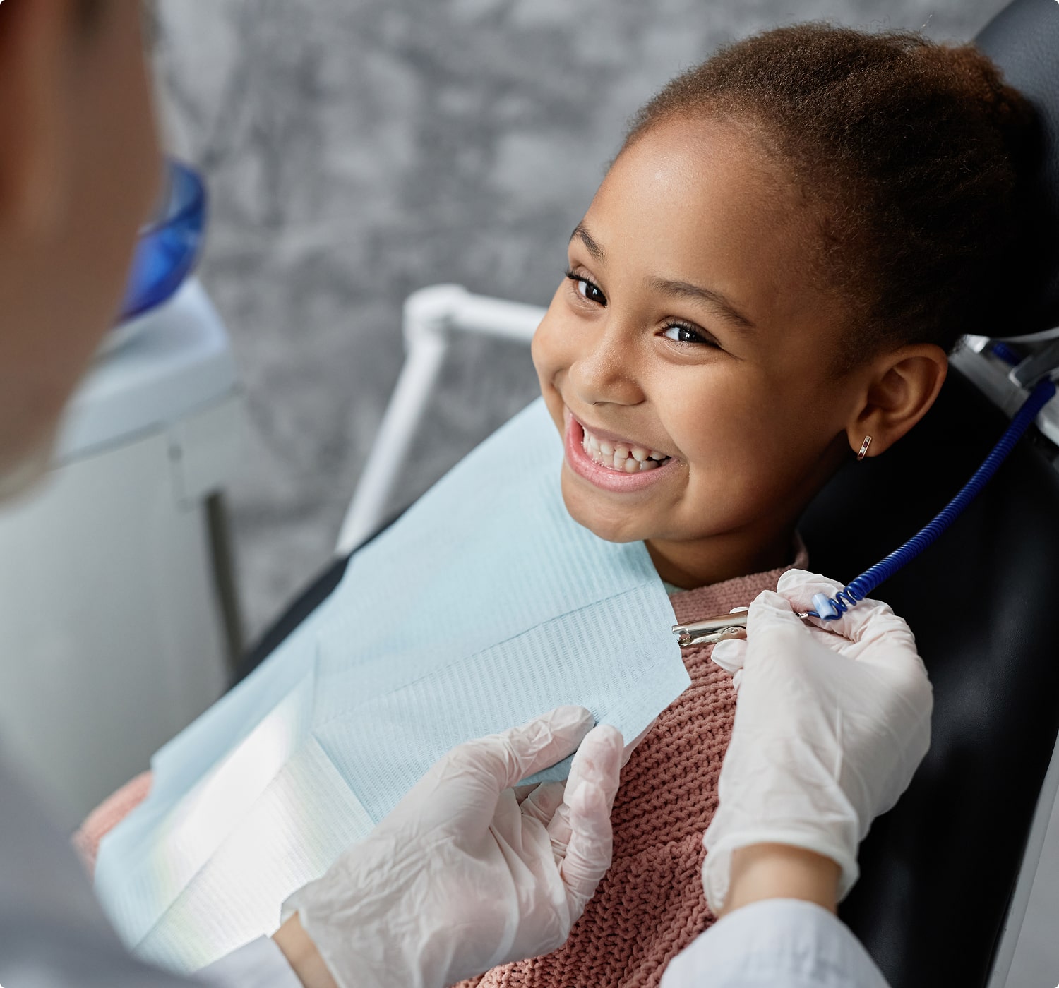 fsc-general-image (13)-min Smiling child sitting in a dental chair while a dentist prepares for a checkup, promoting positive dental visits.