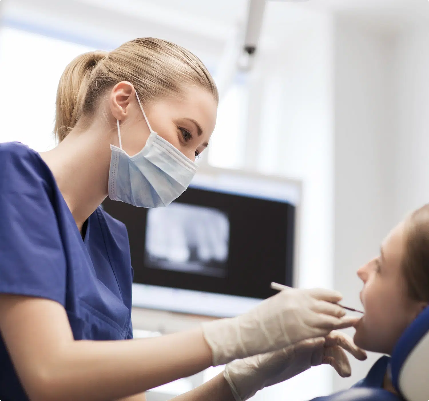 fsc-general-image (18)-min Dentist in mask and gloves examines a patient's mouth with dental tools in a clinical setting.