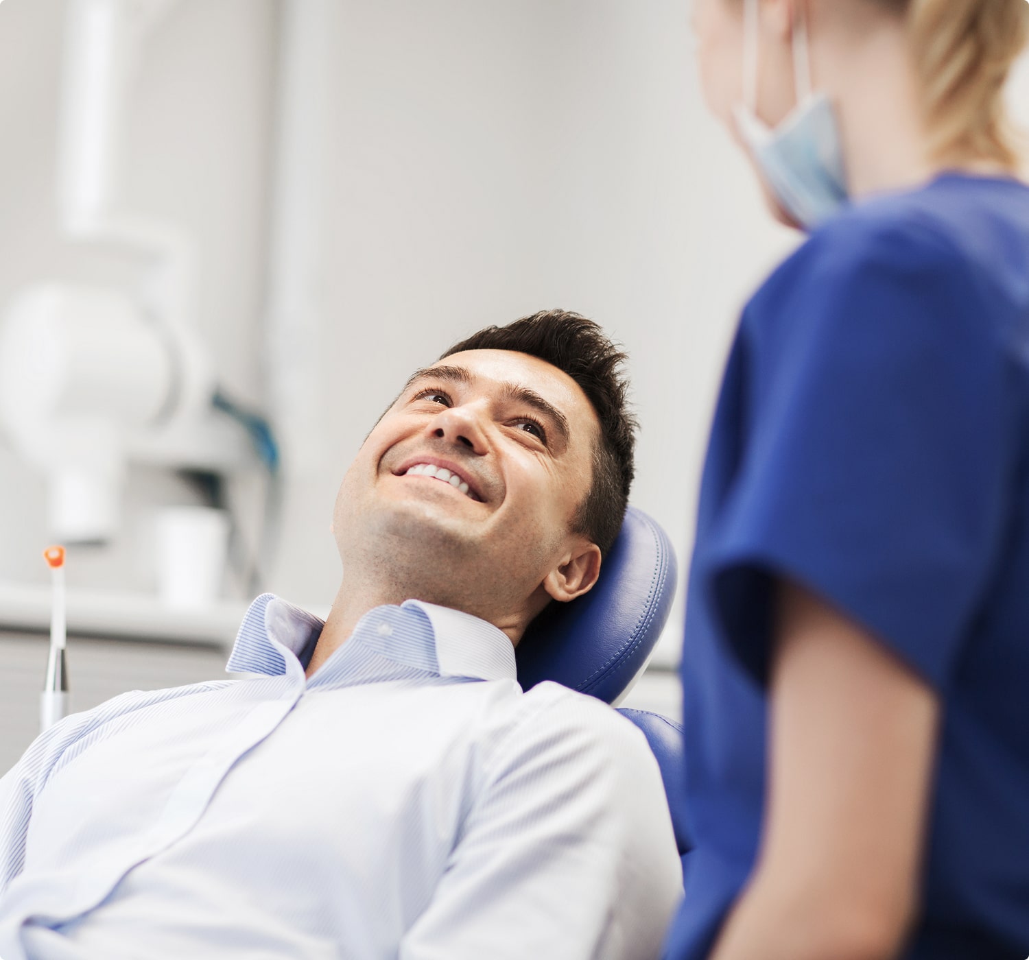 fsc-general-image (19)-min Smiling man reclining in a dental chair, looking up at a dental professional in conversation.