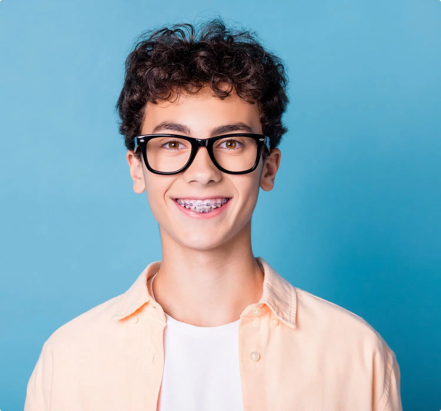 fsc-general-image (2)-min Smiling teen with braces and glasses poses confidently with Invisalign