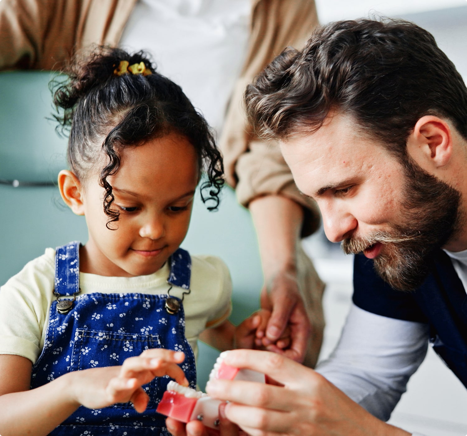 Dentist showing a young girl how to brush teeth using a dental model.