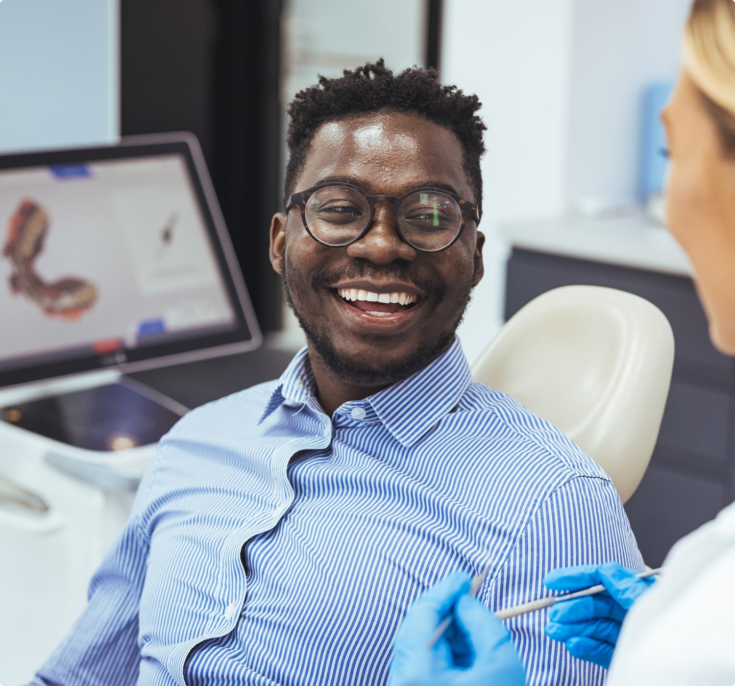 Smiling man in dental chair talking with dentist, showing satisfaction with treatment.