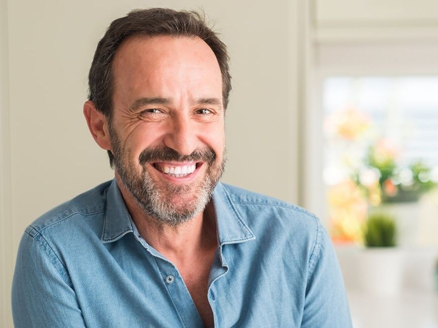 Restorative bridges dentures image Middle-aged man in blue button up smiling