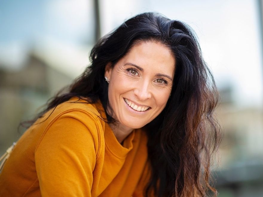 Restorative crowns inlays onlays image Middle-aged woman with long, dark hair wearing yellow shirt smiling