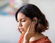 A woman grabbing her left jaw in discomfort
