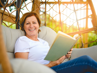 A woman with short brown hair smiling while reading a book.